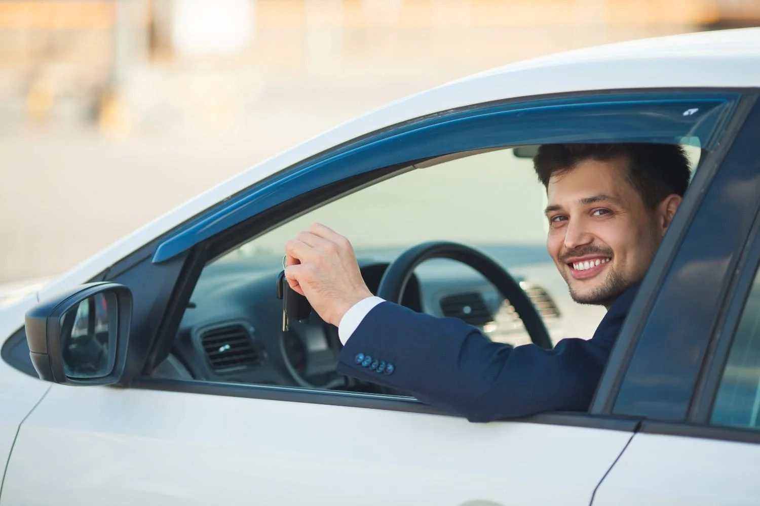 Driver smiling from behind the wheel of a parked car